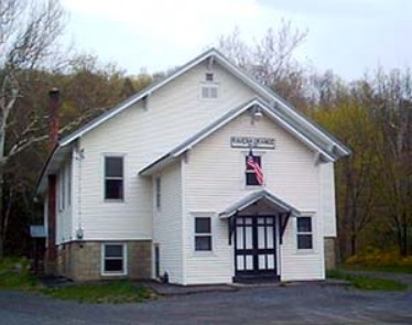 The white two-story Ravena Grange Hall with an American flag above the front entrance